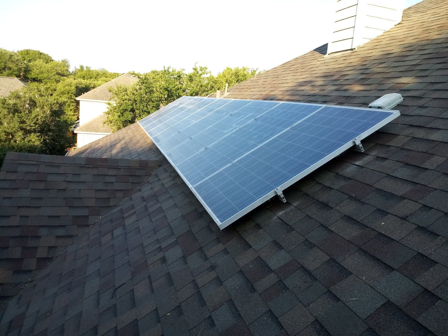 Solar panels mounted on a shingled roof in bright sunlight