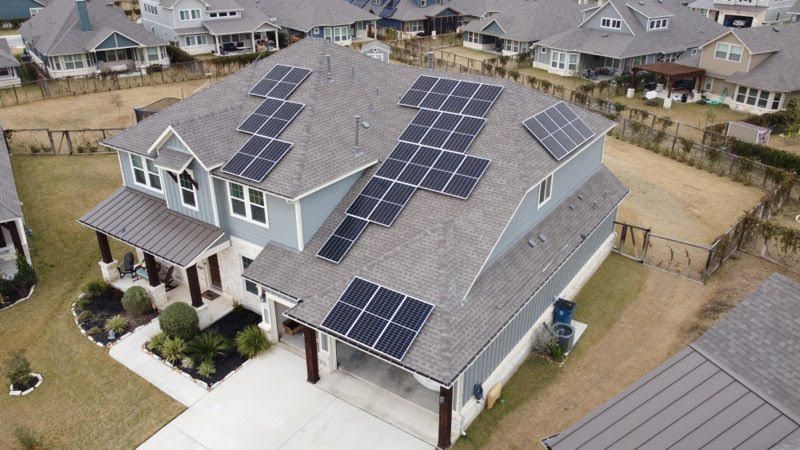 Aerial view of a suburban house with multiple solar panels on its roof.