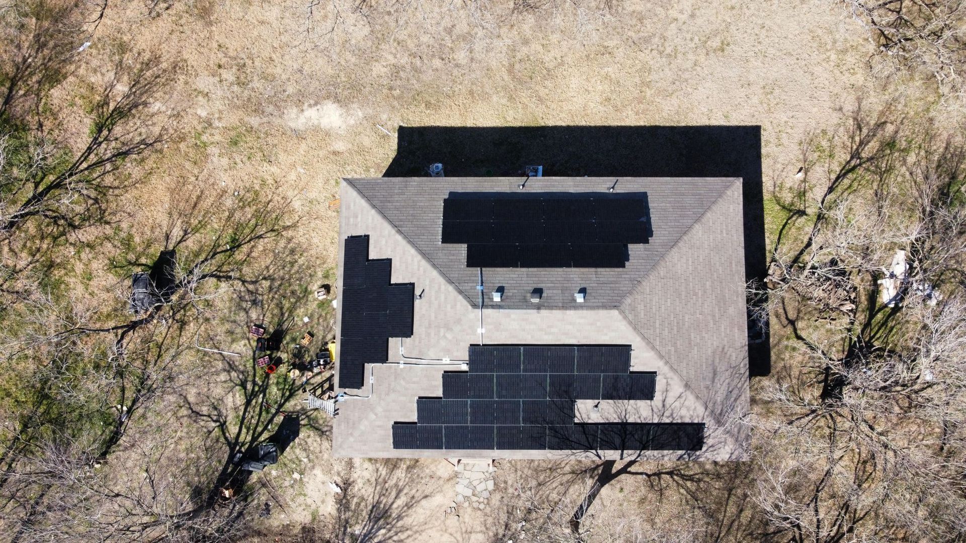 Aerial view of a house roof with solar panels surrounded by trees