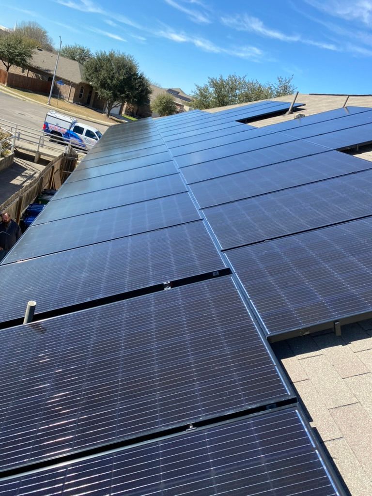 Roof with blue solar panels installed on a sloped rooftop in bright sunlight