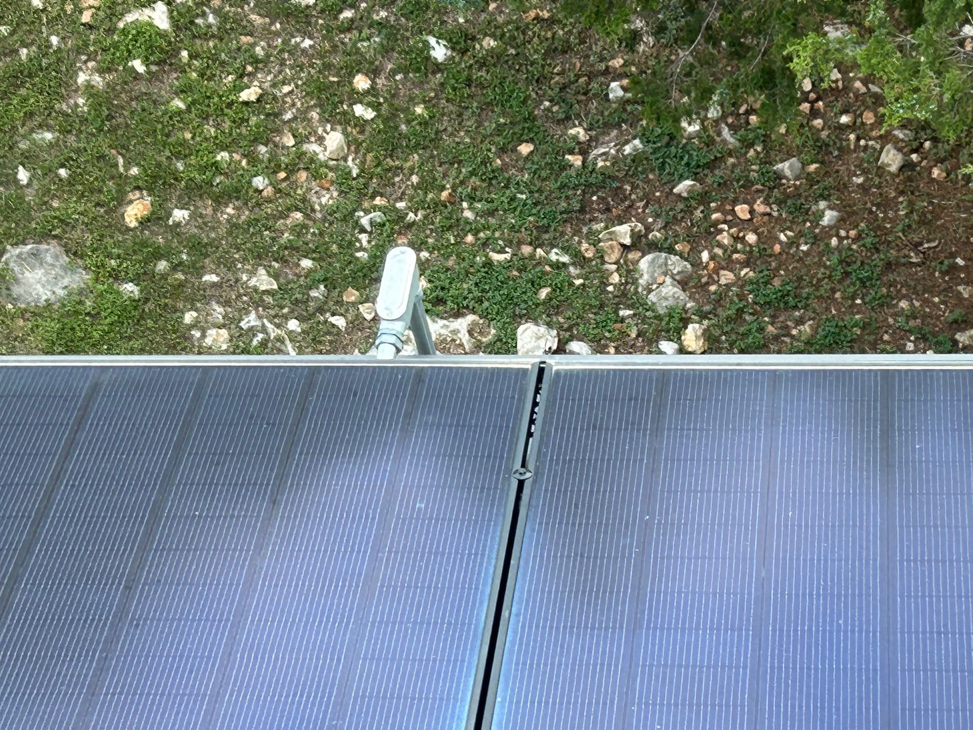 Solar panels beside a grassy yard with a small white fixture at the edge