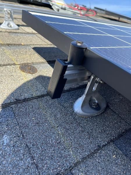 Solar panel mount on a shingled roof with metal support brackets and conduit.