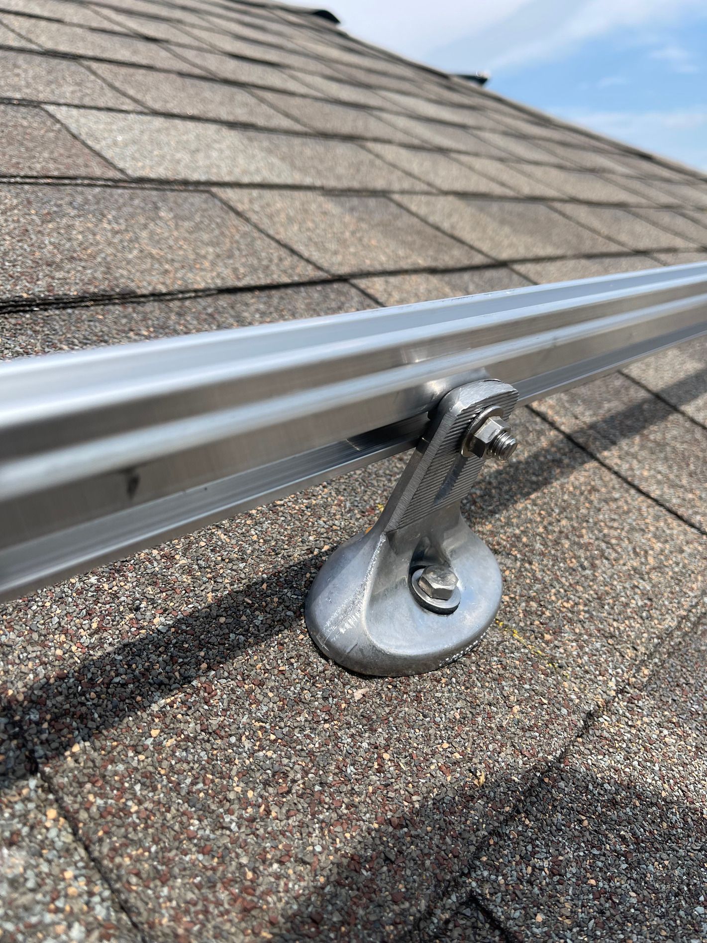 Roof safety anchor mounted on shingled roof with metal rail system
