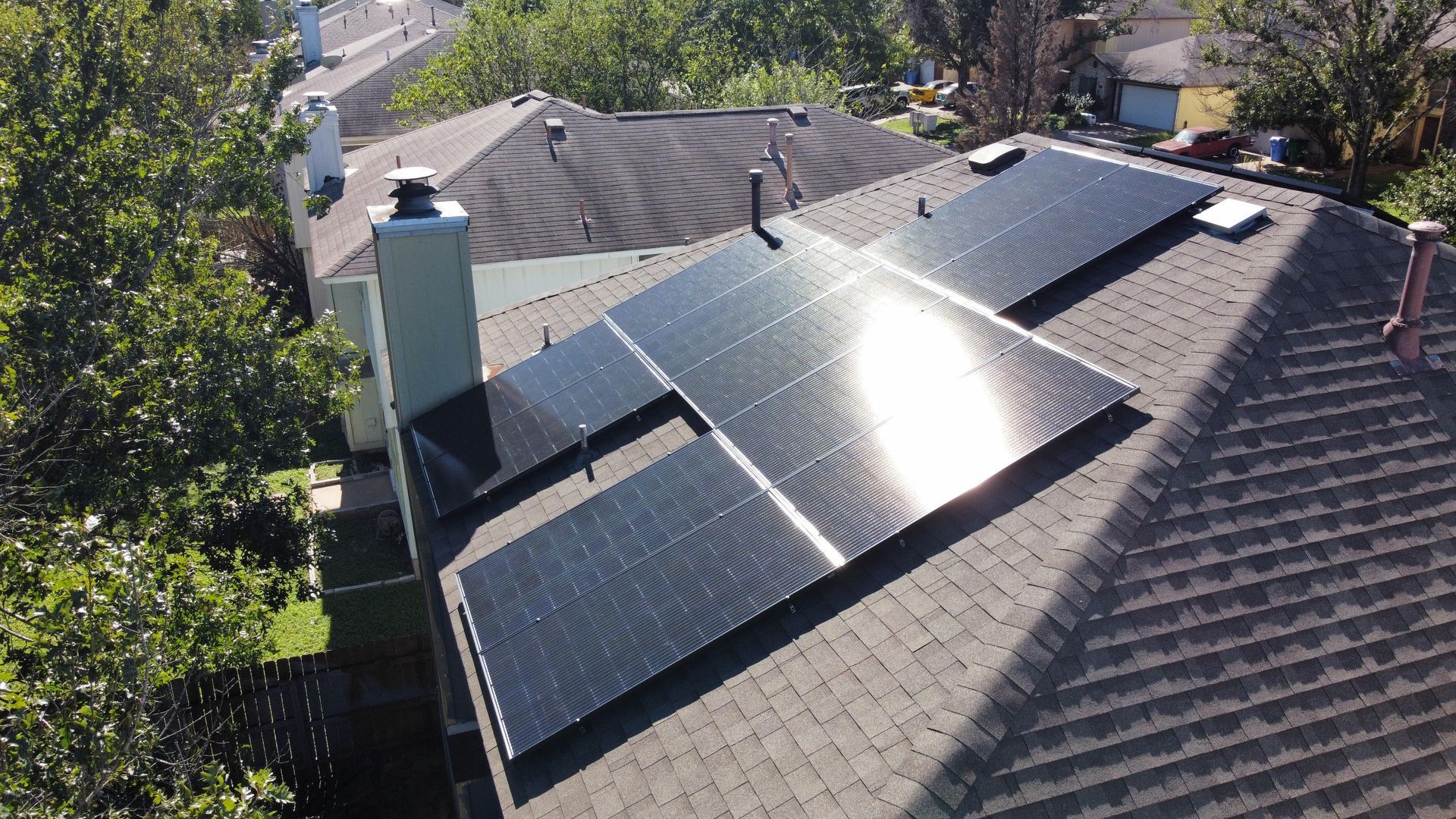 Rooftop solar panels on a house, with sunlight reflecting off the panels.