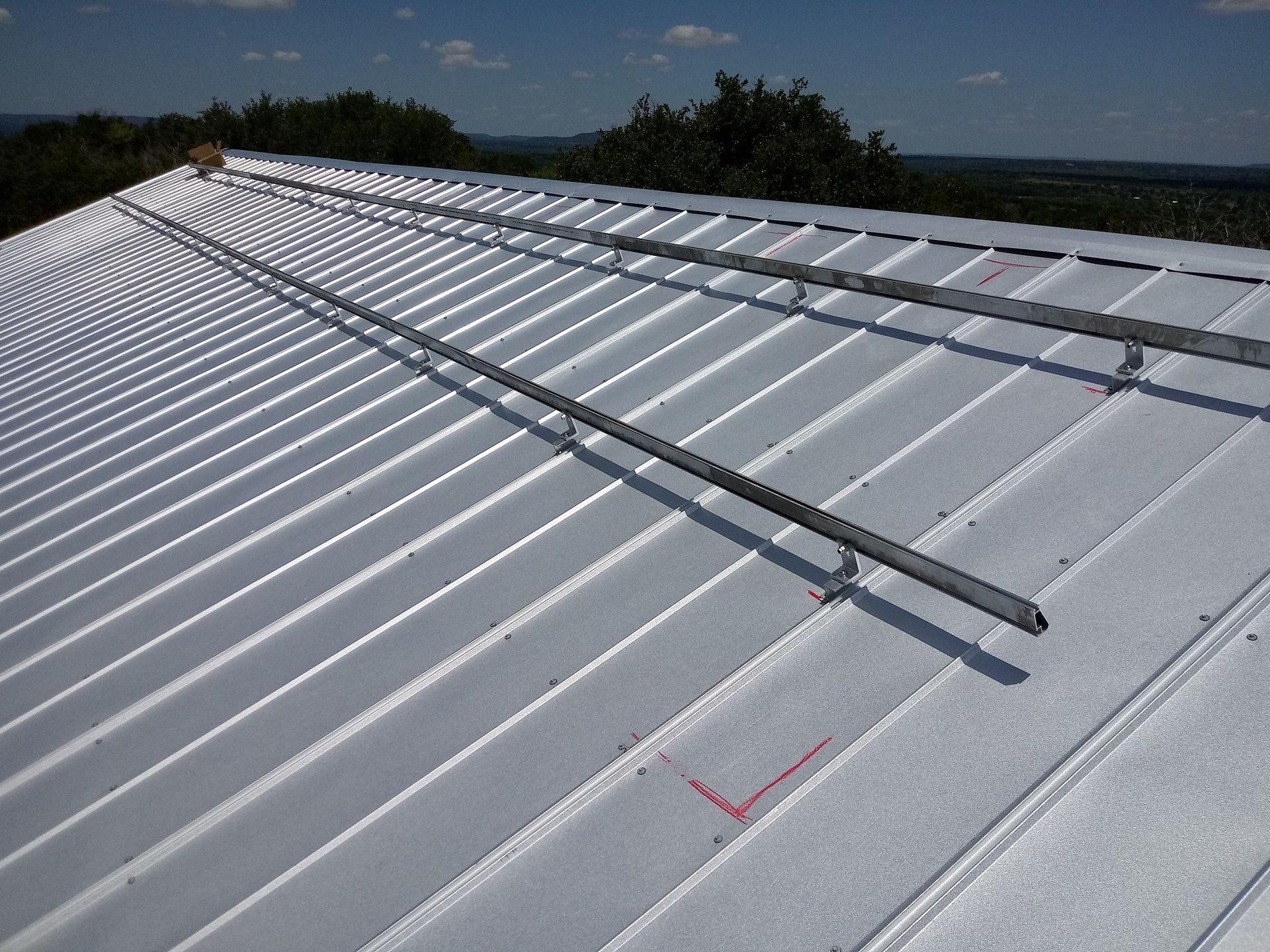 White metal roof with long silver rails under a clear sky
