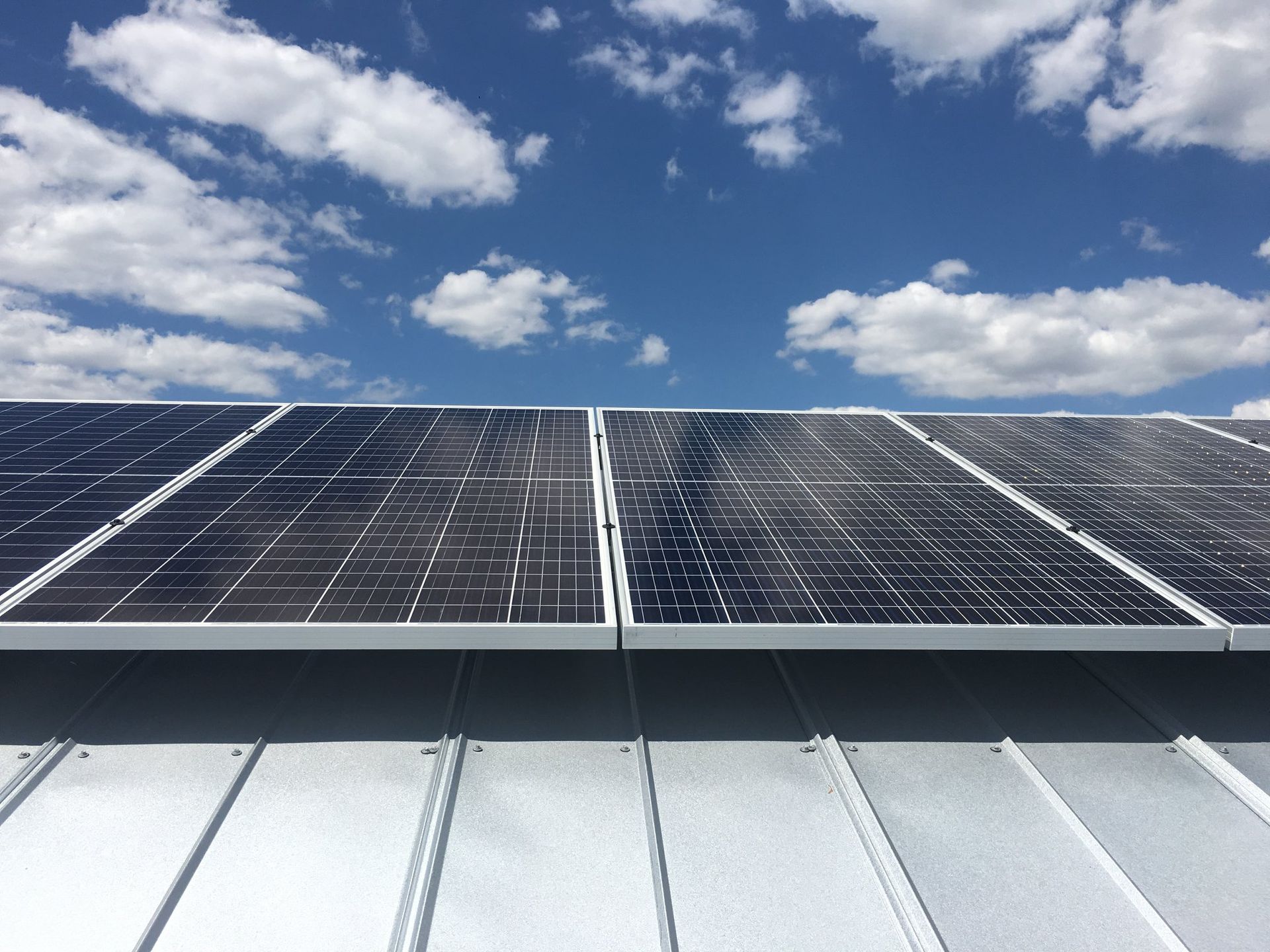 Solar panels on a rooftop beneath a blue sky with scattered clouds