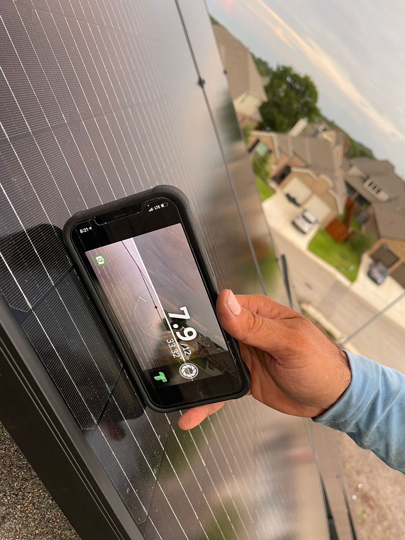 Hand holding a smartphone over rooftop solar panels at sunset