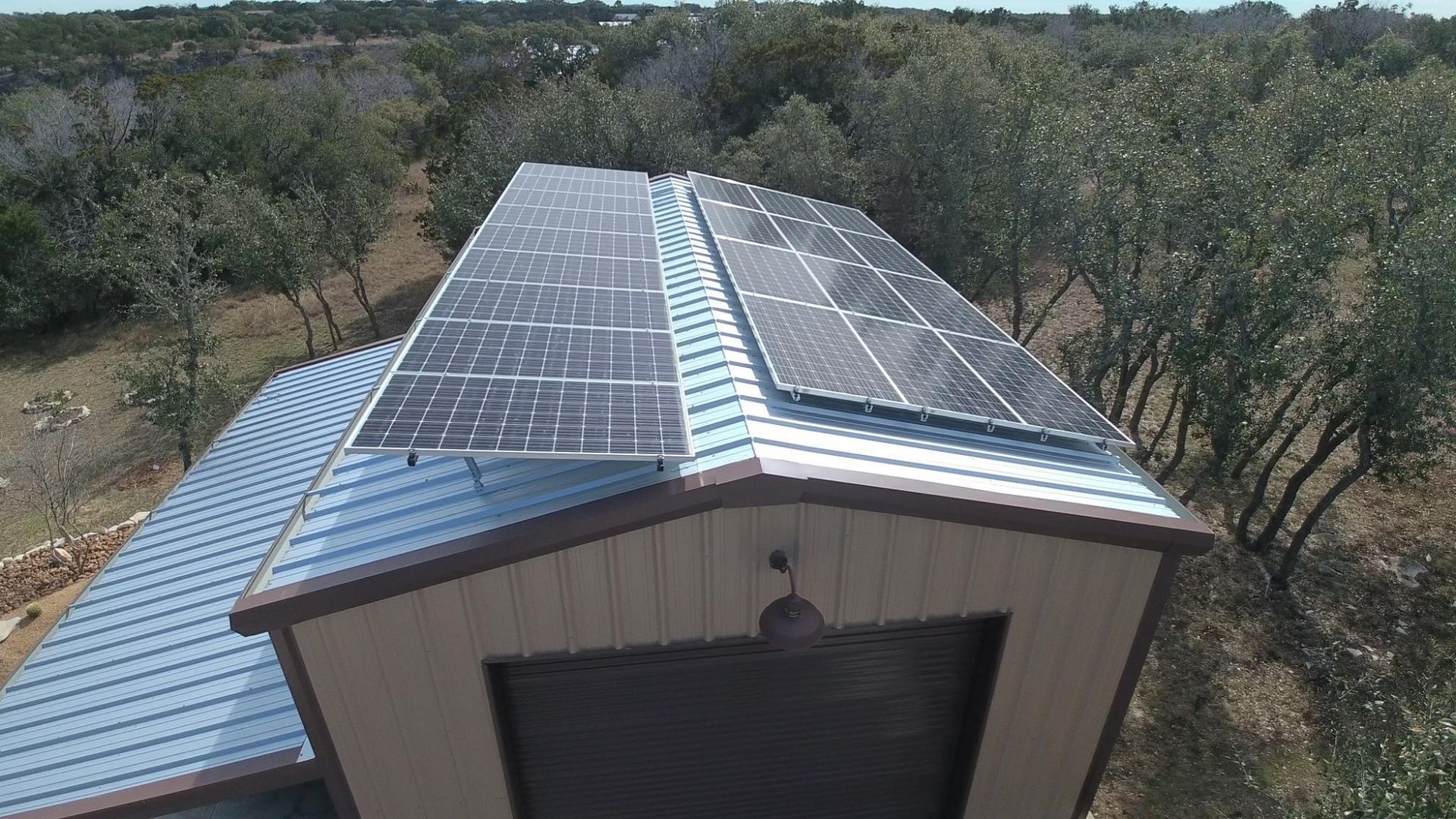 Metal-roofed building with rooftop solar panels in a wooded rural area