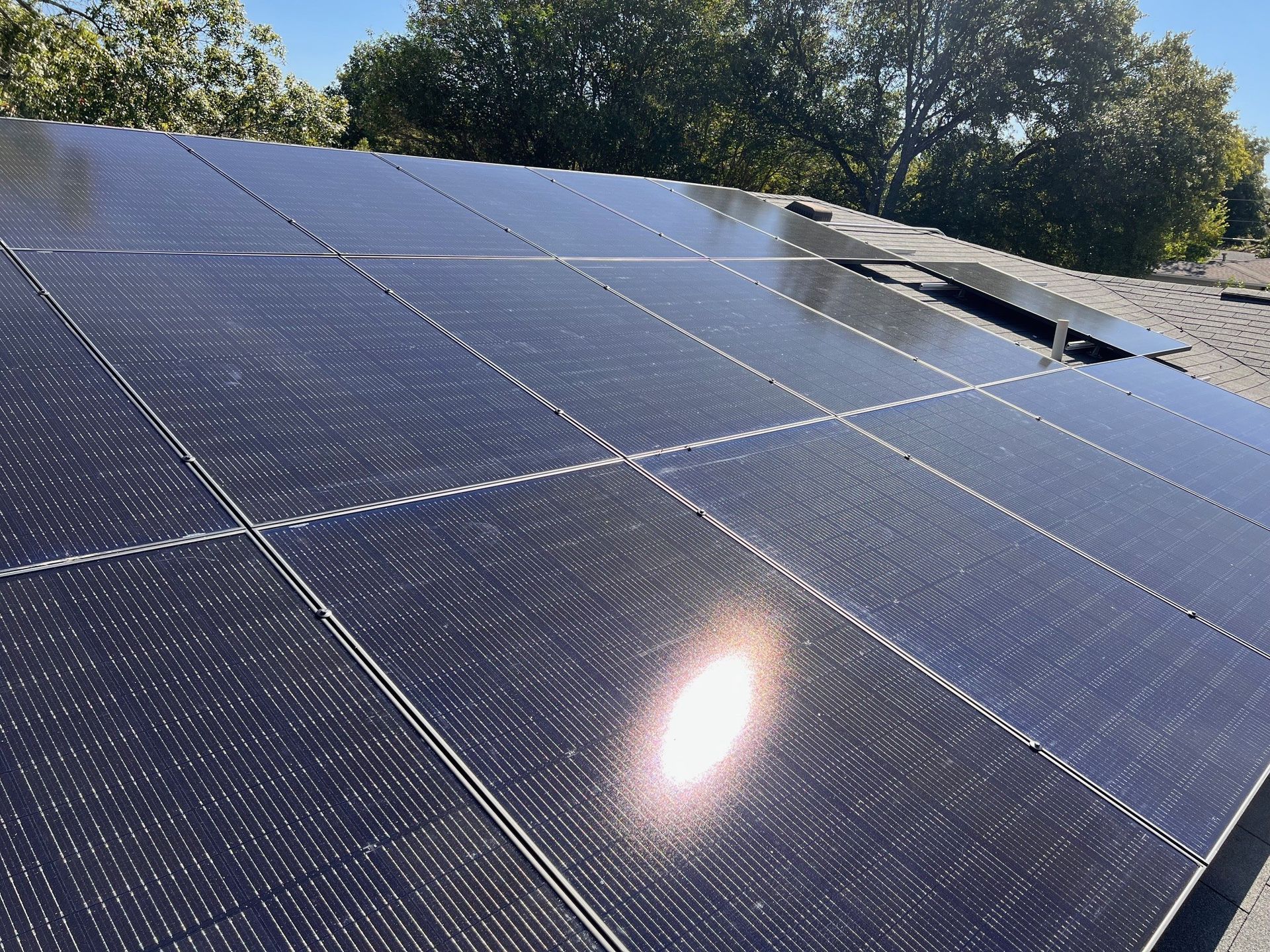 Solar panels on a rooftop with sunlight reflecting off one panel.