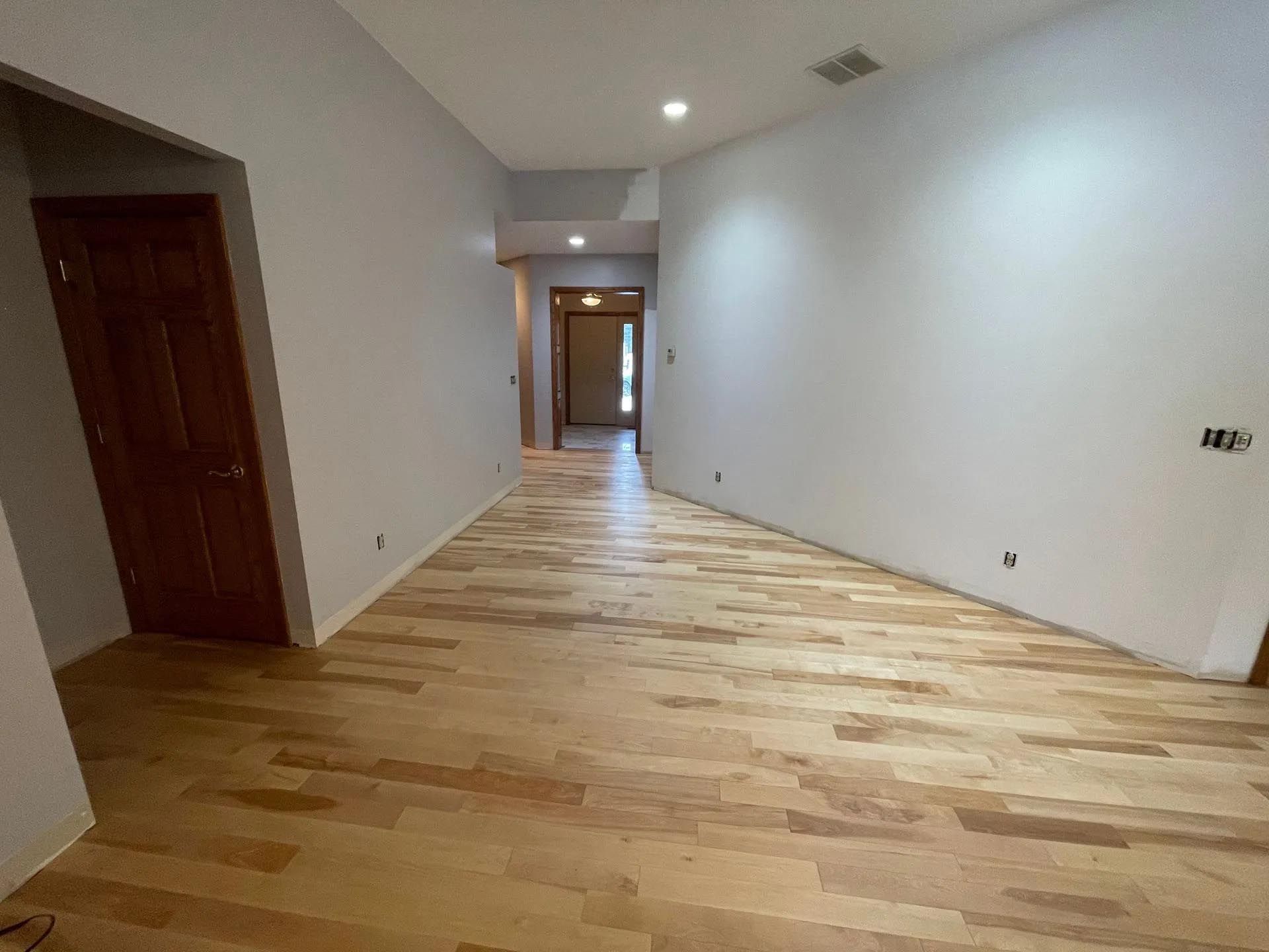 An empty room with hardwood floors and white walls.