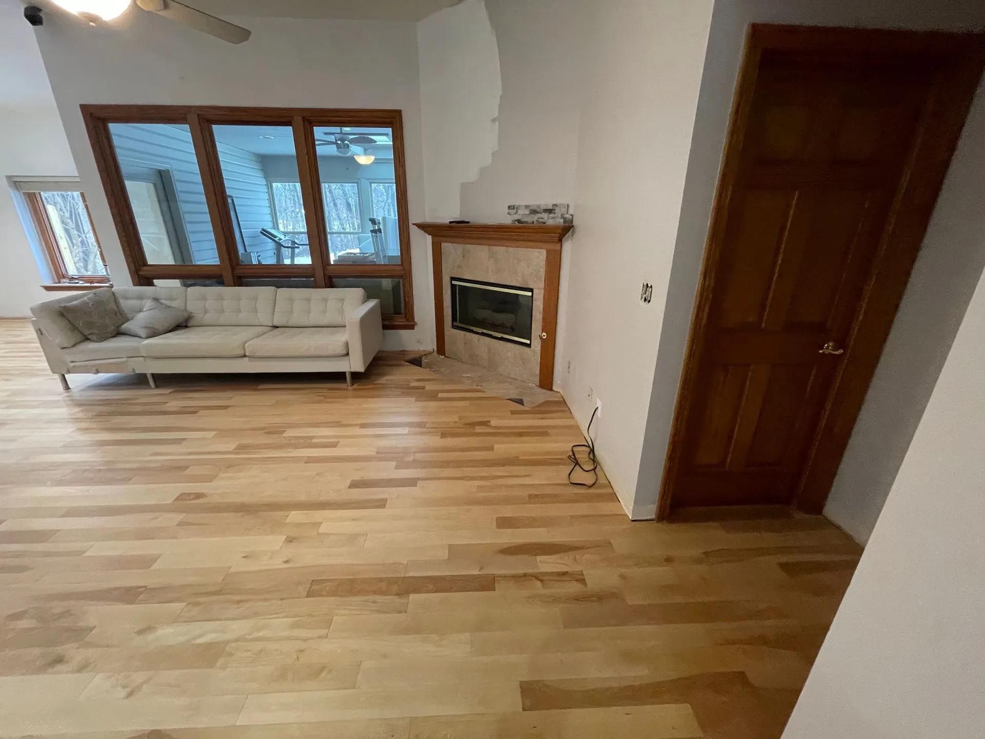 A living room with hardwood floors , a couch , and a fireplace.