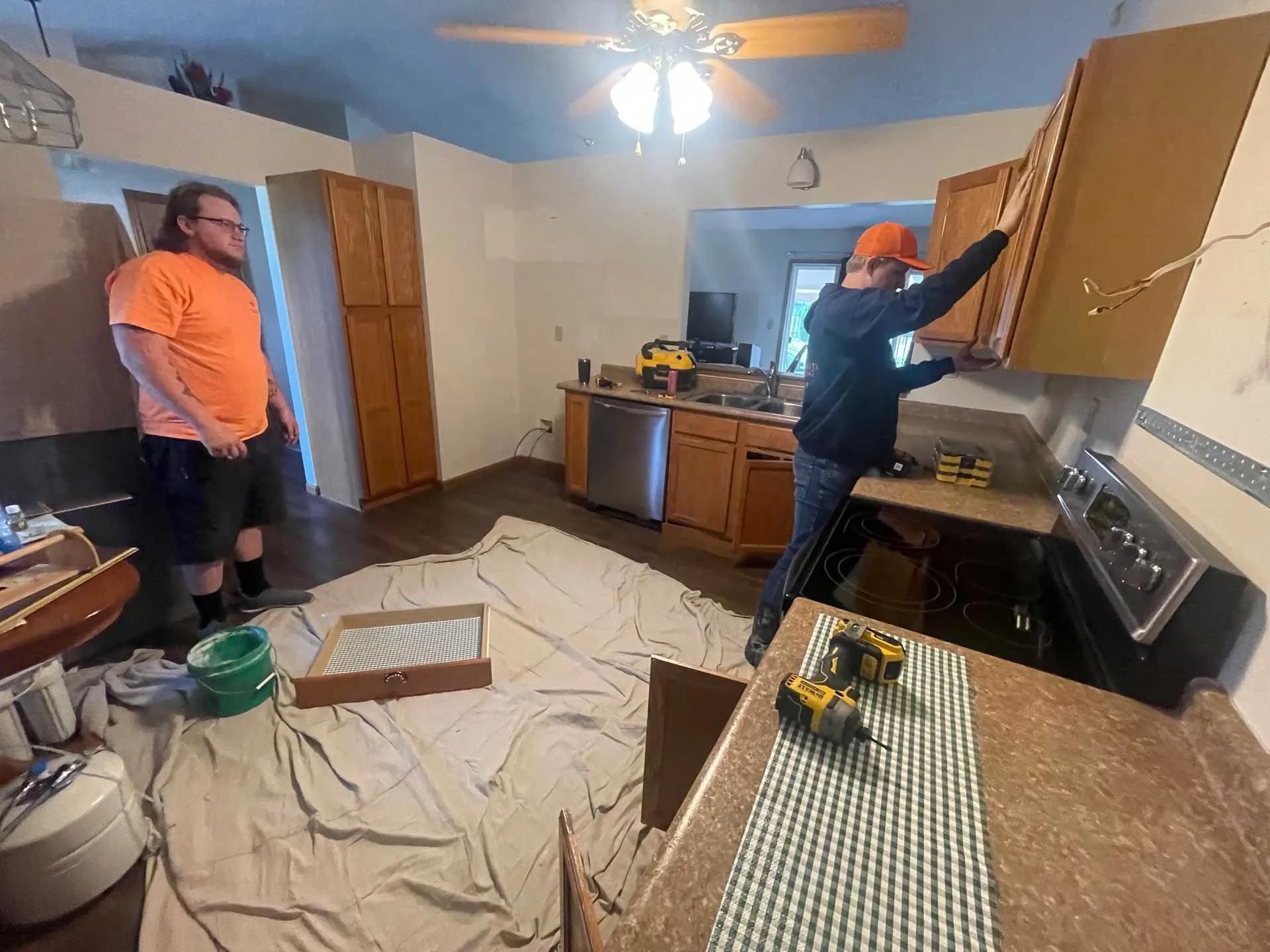 A couple of men are working on a kitchen.