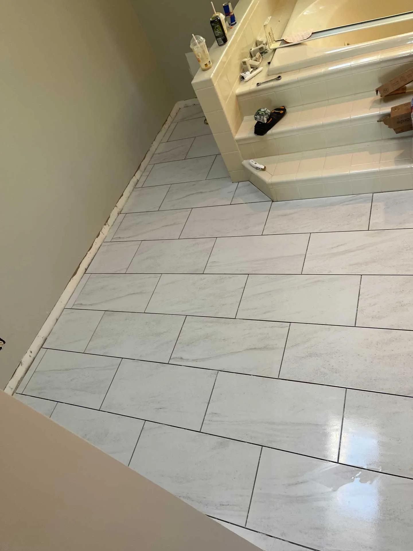 A bathroom with white tile floors and stairs leading to a bathtub.
