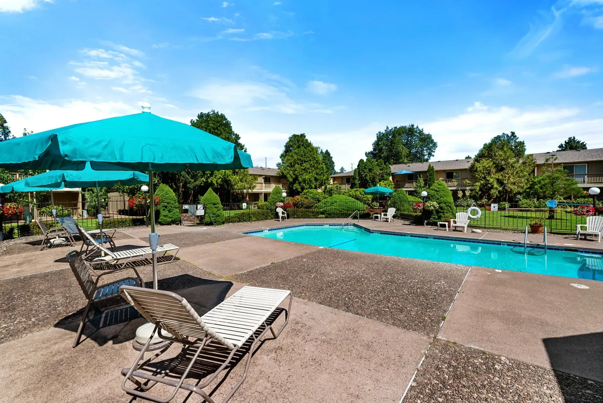 Outdoor pool with turquoise umbrellas, lounge chairs, and clear blue water under a bright sky