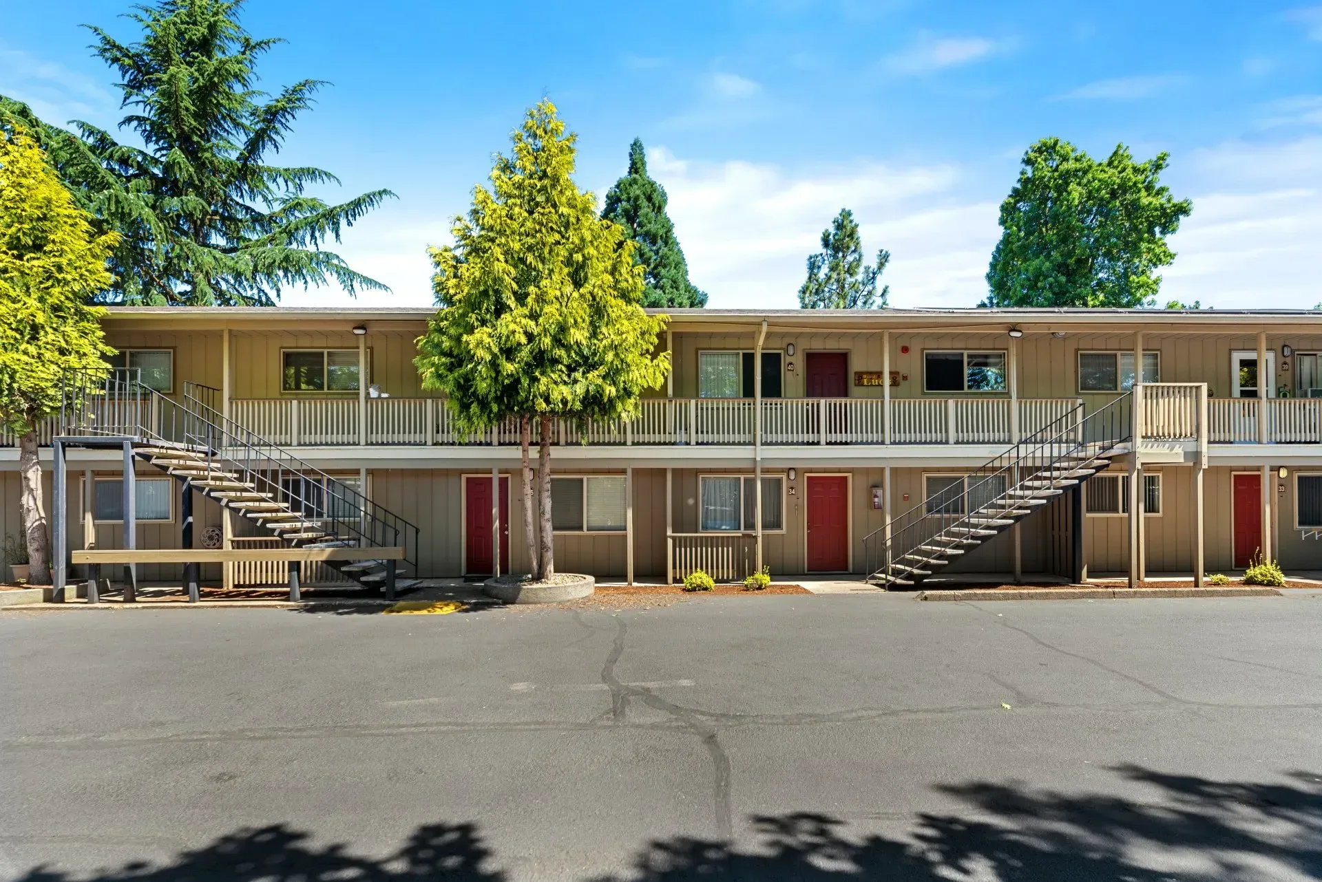 Two-story motel with exterior staircases and balconies under a clear blue sky