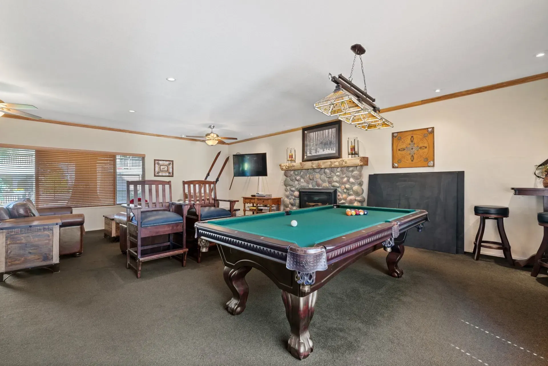 Spacious game room with a green pool table, fireplace, seating area, and wall-mounted TV