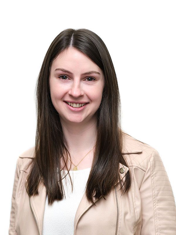 A young woman wearing a leather jacket and a white shirt is smiling for the camera.