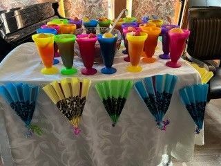Colorful drinks and folded fans arranged on a white tablecloth.