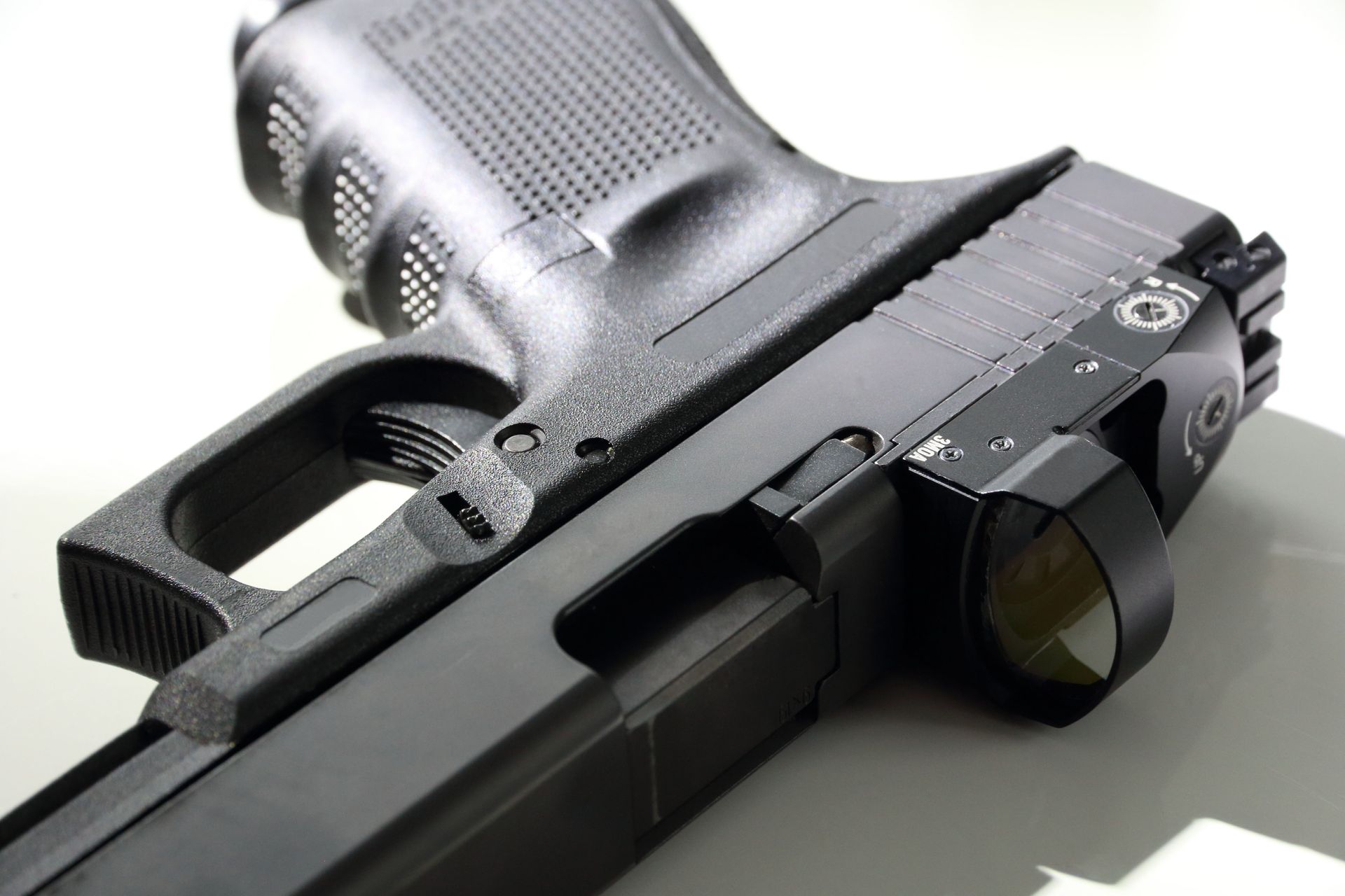 Close-up of a black semi-automatic handgun on a light surface, angled to show the grip and slide.
