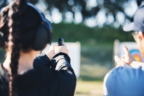 Two people aiming handguns at an outdoor shooting range