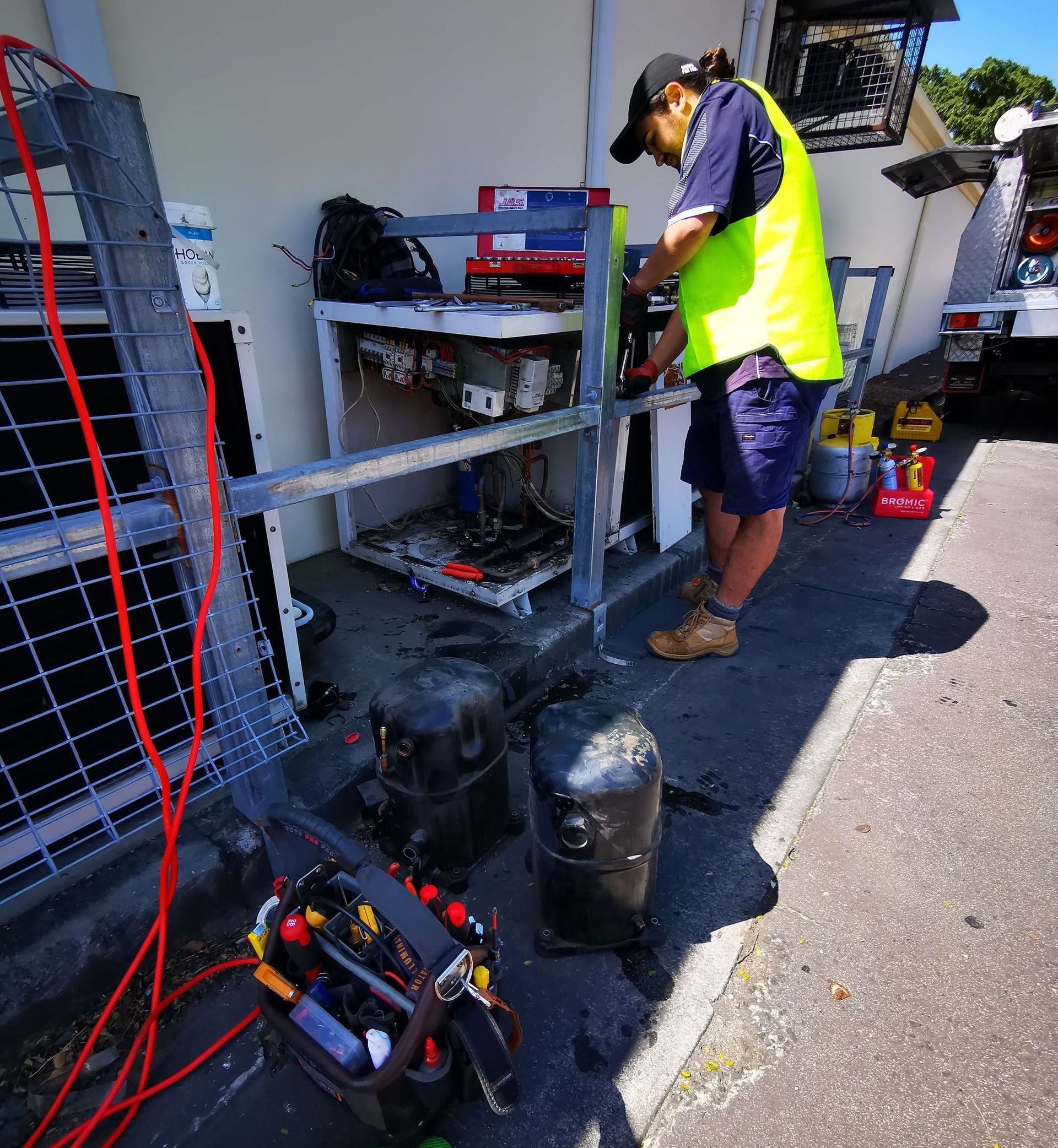 A Man is Standing on a Ladder Fixing a Fan in a Room — Chillzone Refrigeration and Air Conditioning in Bribie Island, QLD