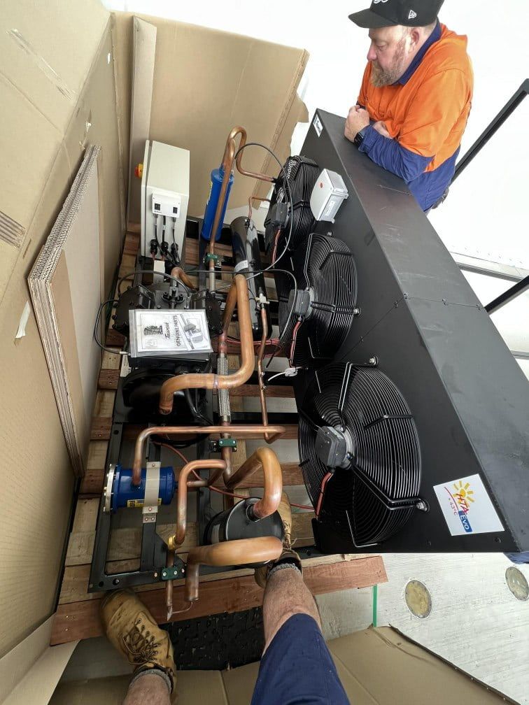 A Man is Working on a Machine in a Cardboard Box — Chillzone Refrigeration and Air Conditioning in Nambour, QLD