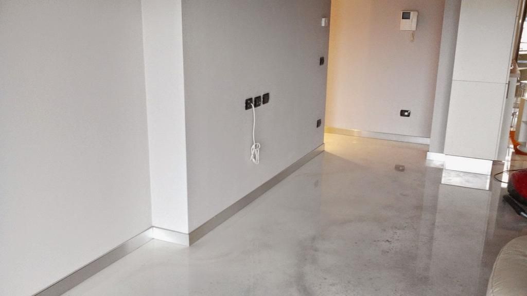 Pareti dipinte di grigio e pavimento in cemento grigio lucido in un interno incompiuto.