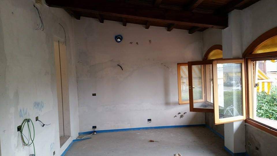 Stanza interna con pareti chiare, soffitto e finestre in legno. Cablaggio e lavori in corso.