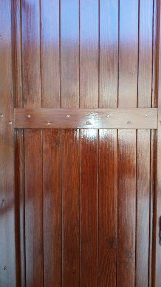 Porta in legno con assi verticali e trave di sostegno orizzontale, tinta marrone.
