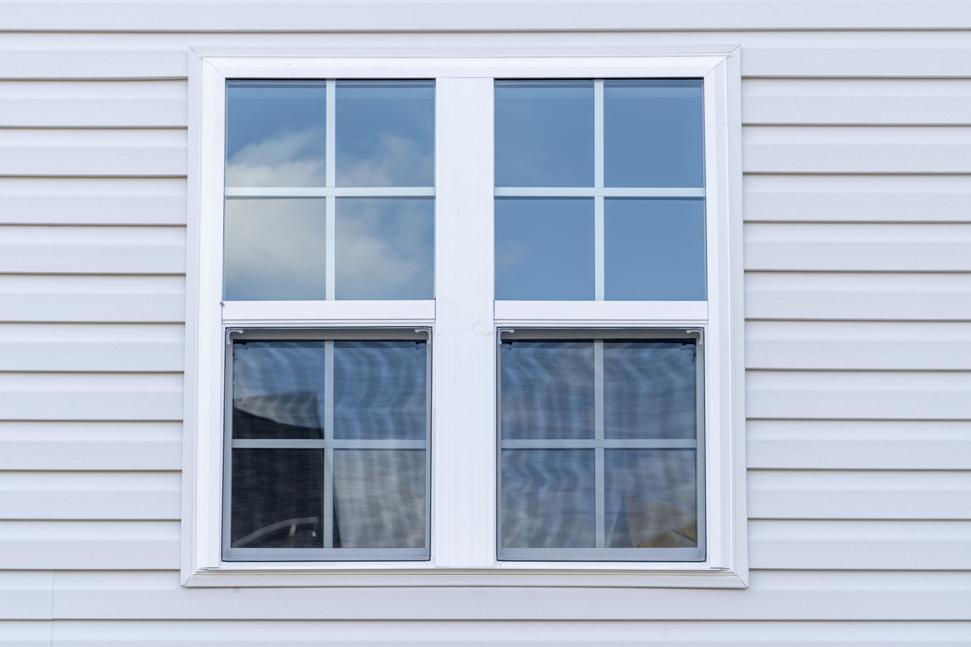 White double-hung window with a 6-pane grid, set in light blue siding.