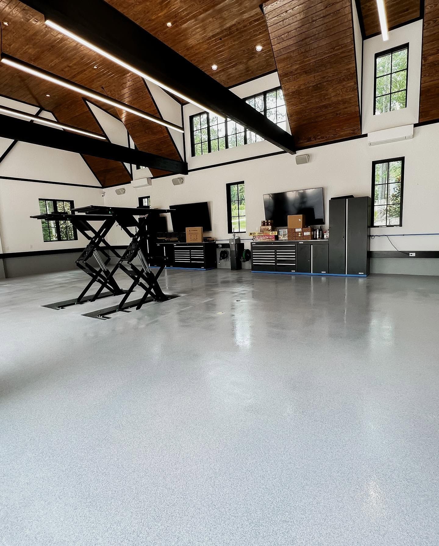 Modern loft interior with polished concrete floor, high wood ceiling, desks, and a black folding chair lift