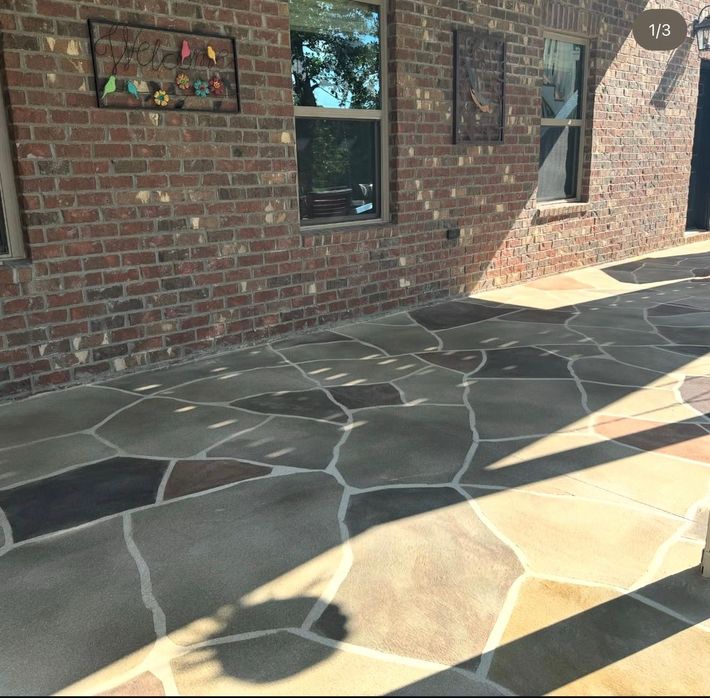 Stone patio beside a house with sliding glass doors and a shaded outdoor seating area