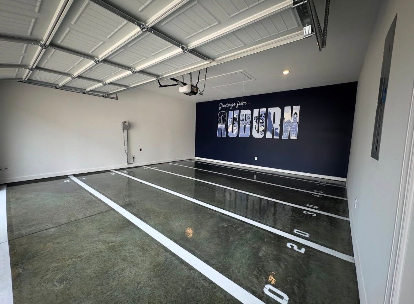 Indoor gym with marked lanes, mirrors, and a dark accent wall in a bright room
