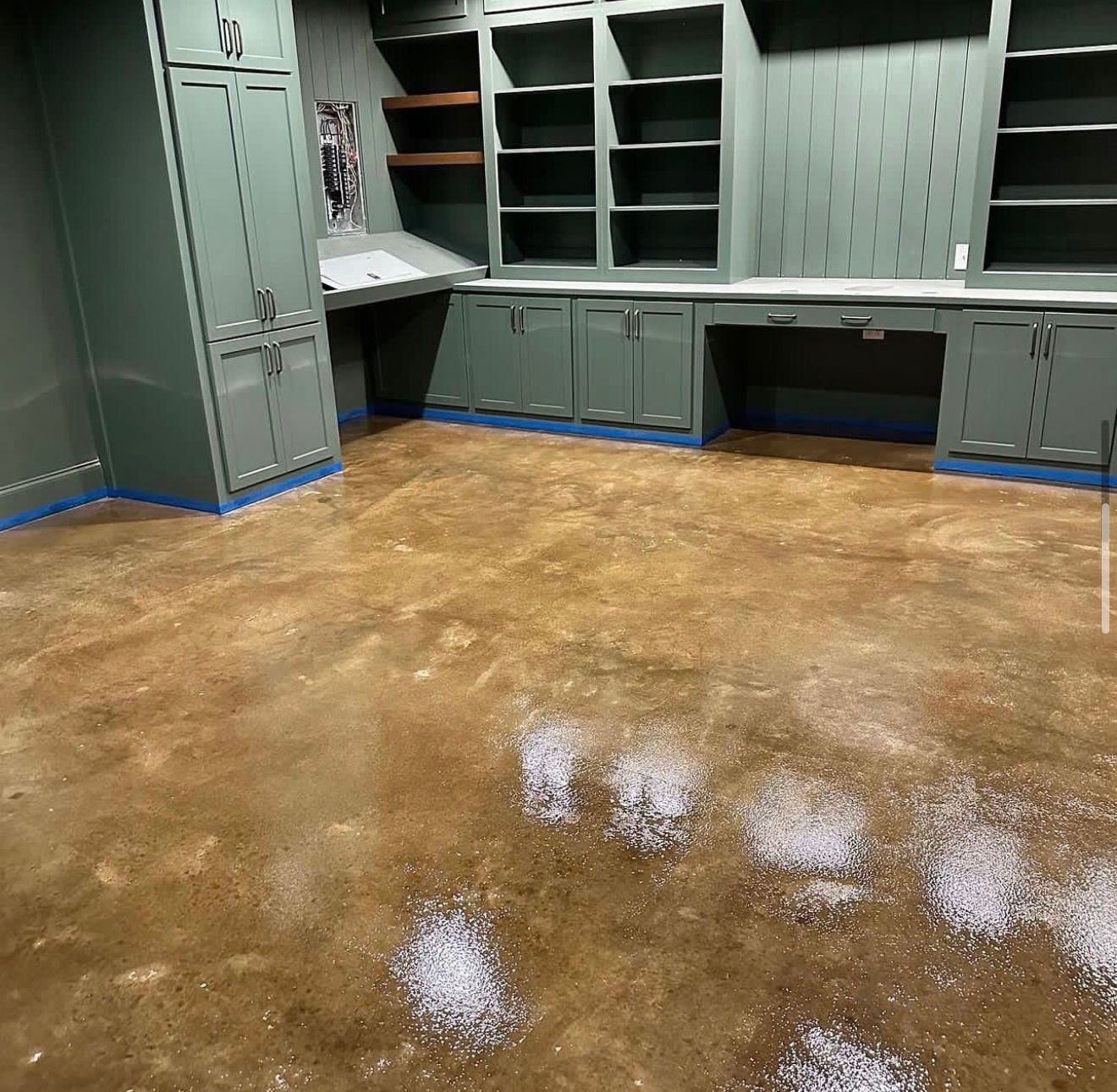 Empty utility room with gray cabinets and a wet brown floor reflecting light