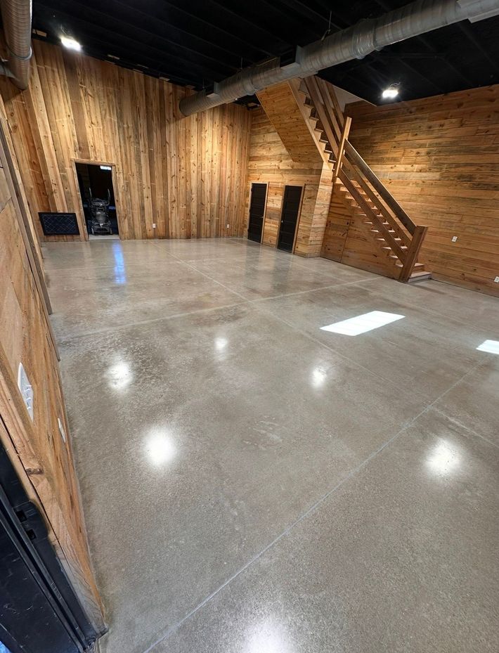Empty industrial warehouse with polished concrete floor and bright open doorway in the background