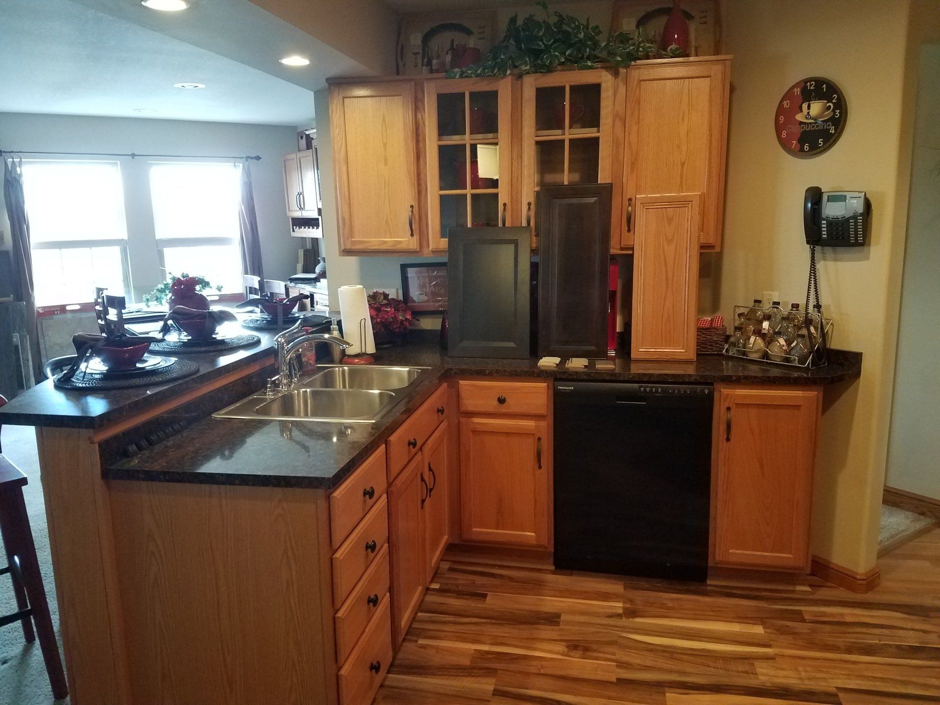 Kitchen remodeling Kitchen with light wood cabinets, dark countertops, and stainless steel sink. A black dishwasher