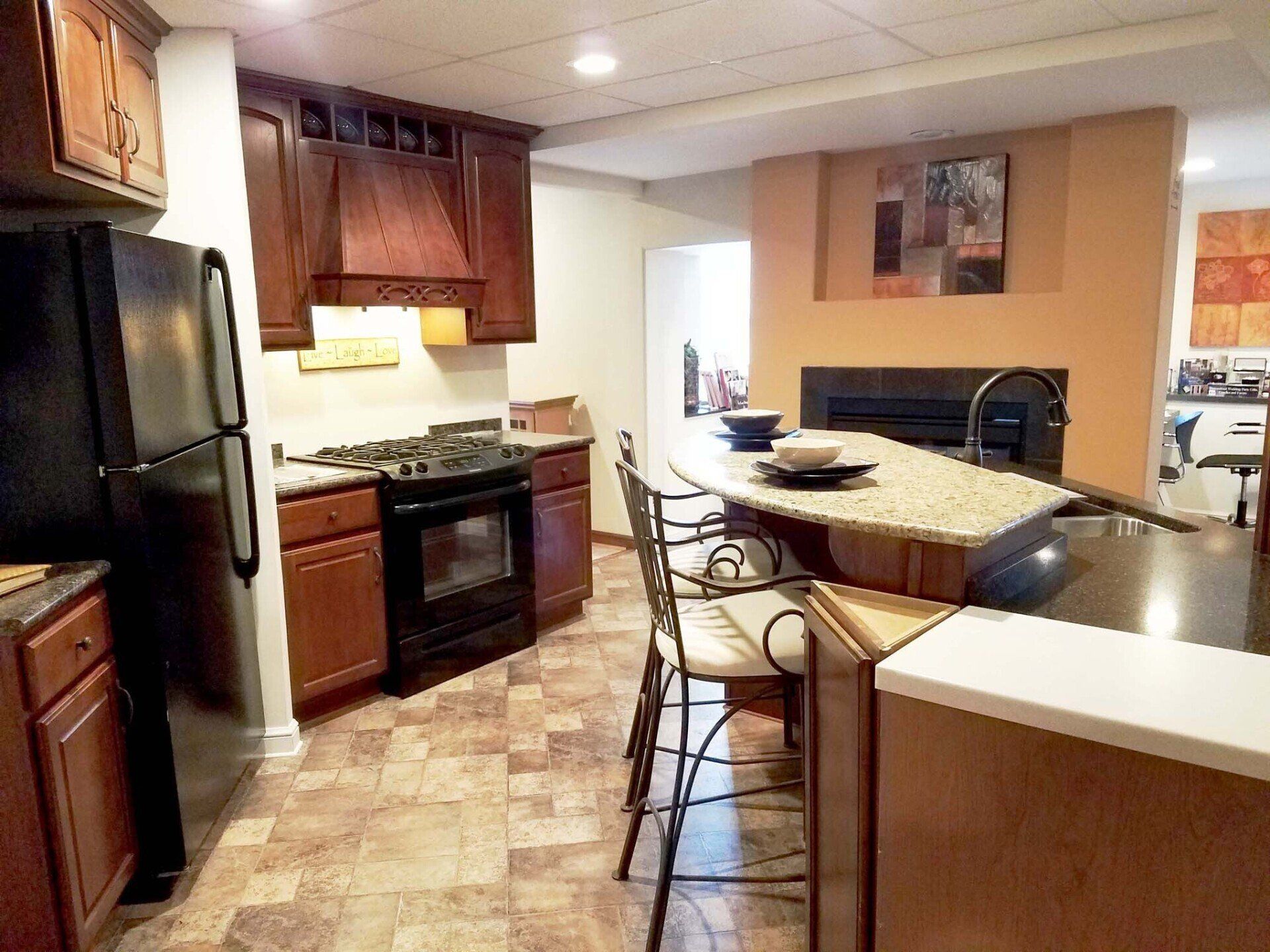 Kitchen with brown cabinets, black appliances, and an island with seating.