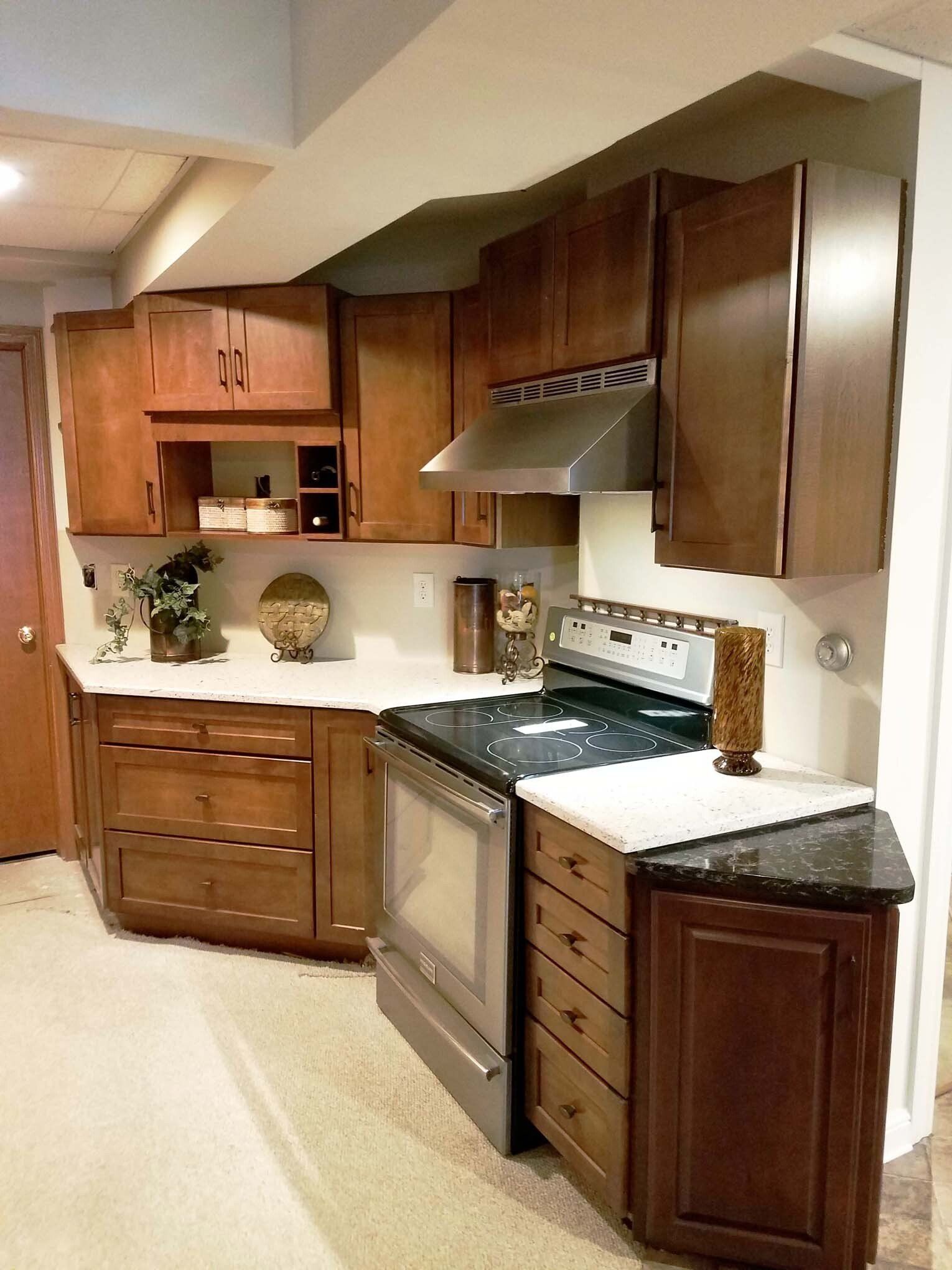 Small kitchen with wood cabinets and stainless steel appliances, white countertops, neutral walls.