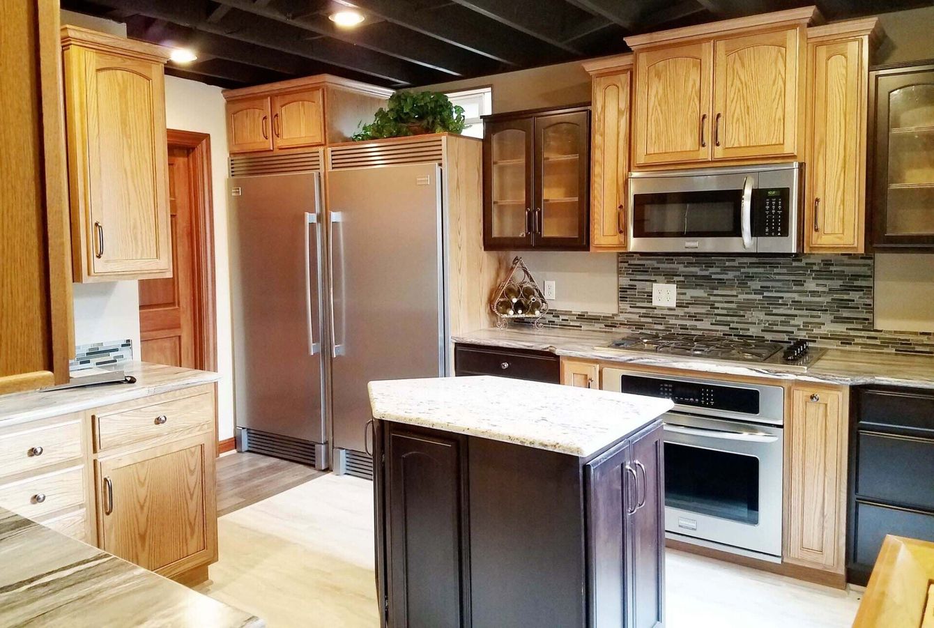 Kitchen remodeling with light wood cabinets, stainless steel appliances, and a dark island with a granite countertop.