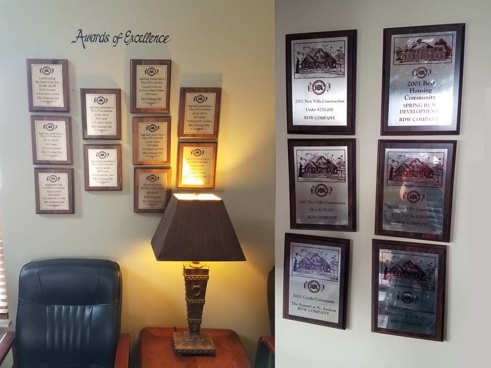 remodeling awards Wall displaying framed plaques and awards, a lamp, and a black office chair.