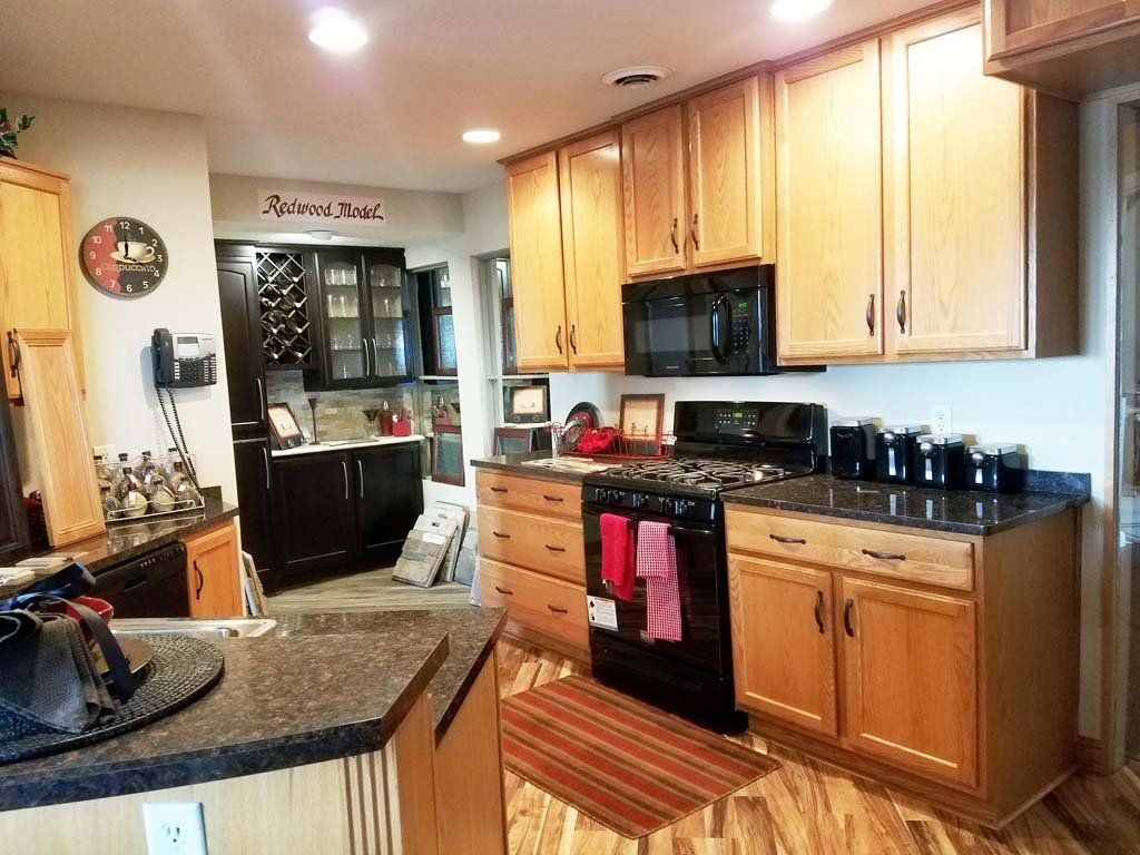 Kitchen with light brown cabinets, black appliances, and dark countertops.