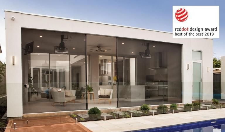Open glass doors lead to an outdoor patio with green grass and a shade sail.