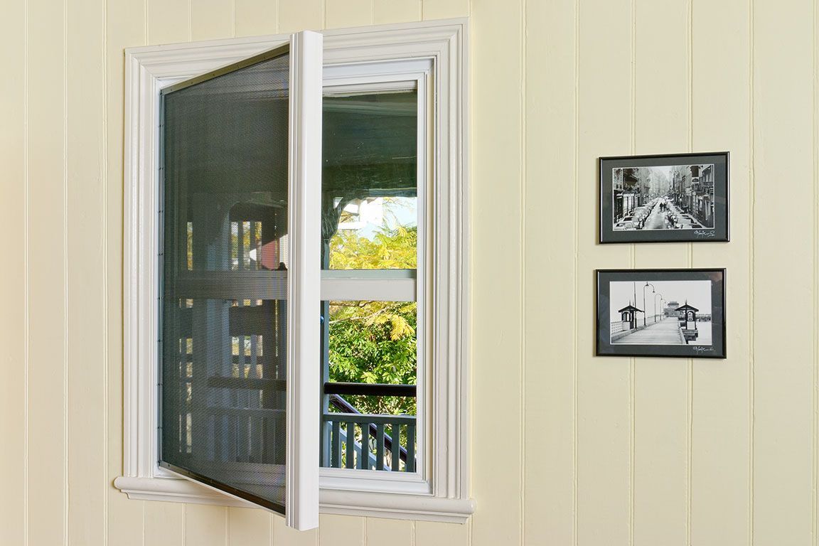 Open window with screen. White trim, yellow siding, two framed photos.