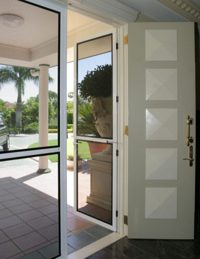 Open front door with screen door and a tiled porch. Palm trees and urn visible.