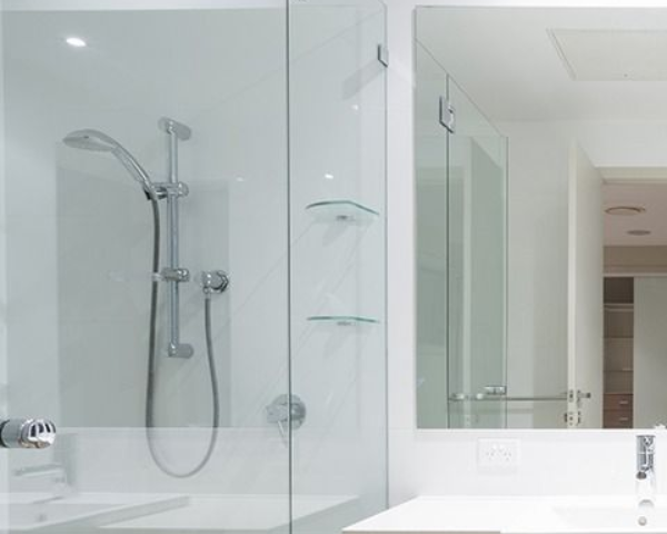 Modern white bathroom with double sink vanity, large mirror, and glass shower enclosure.