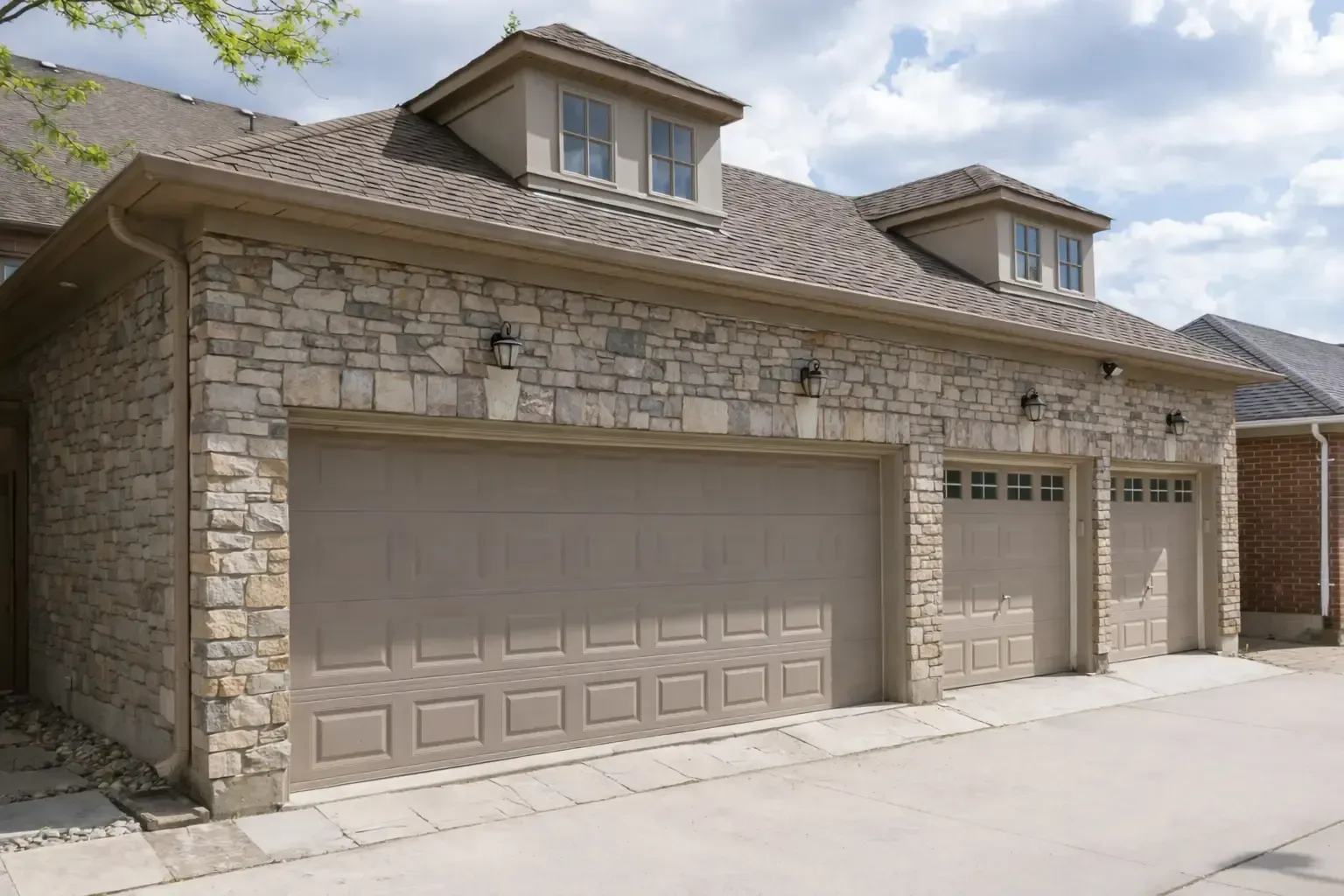 Grande Prairie Handyman: Two-car garage with a stone facade, two green garage doors, and a concrete driveway.