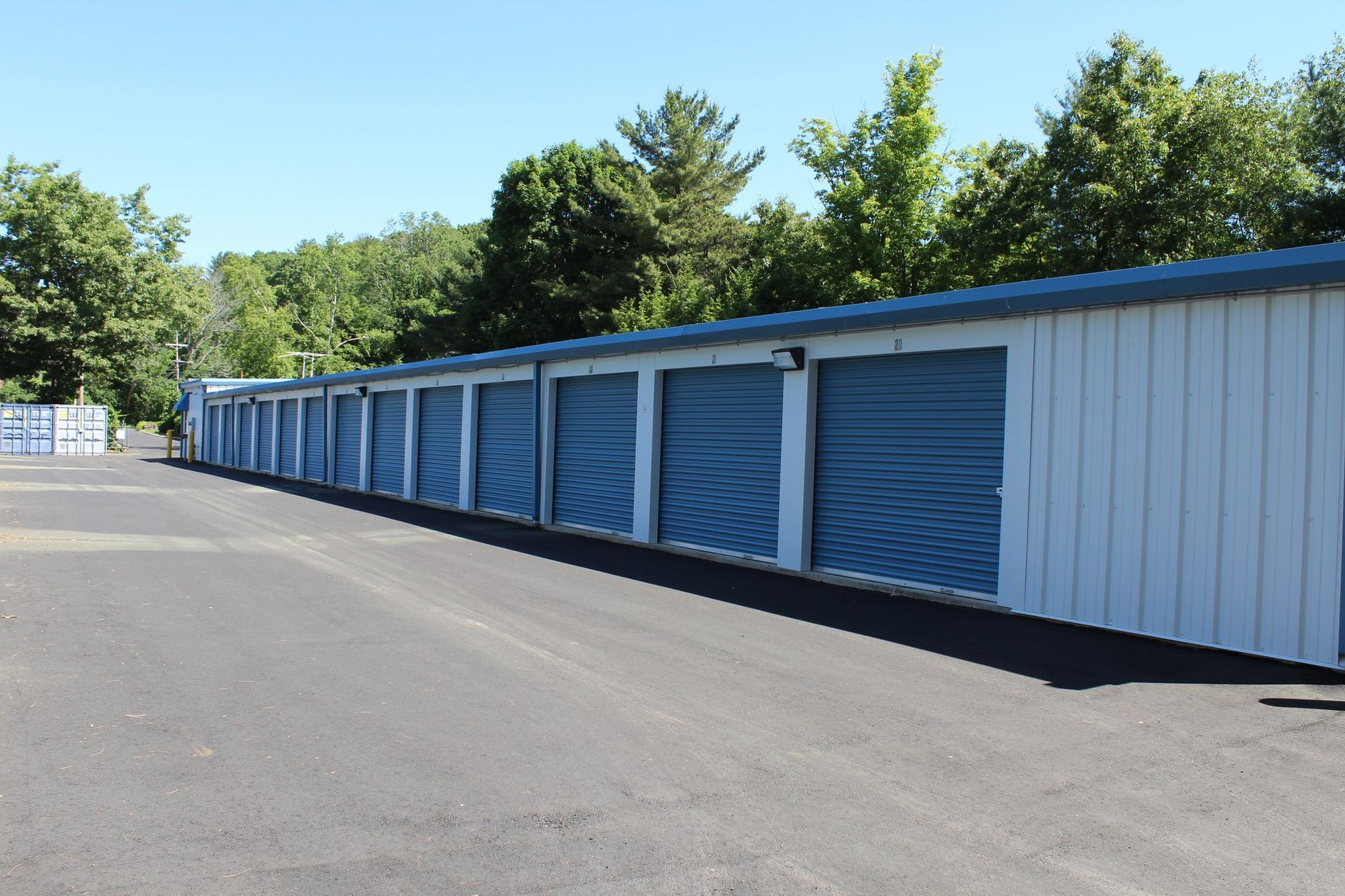 A row of shipping containers are lined up in a parking lot