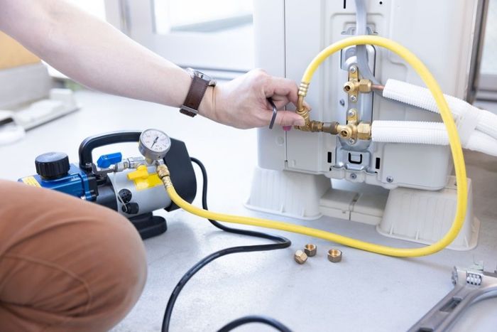 Technician connecting a yellow gas hose to a wall-mounted valve with pressure gauges nearby