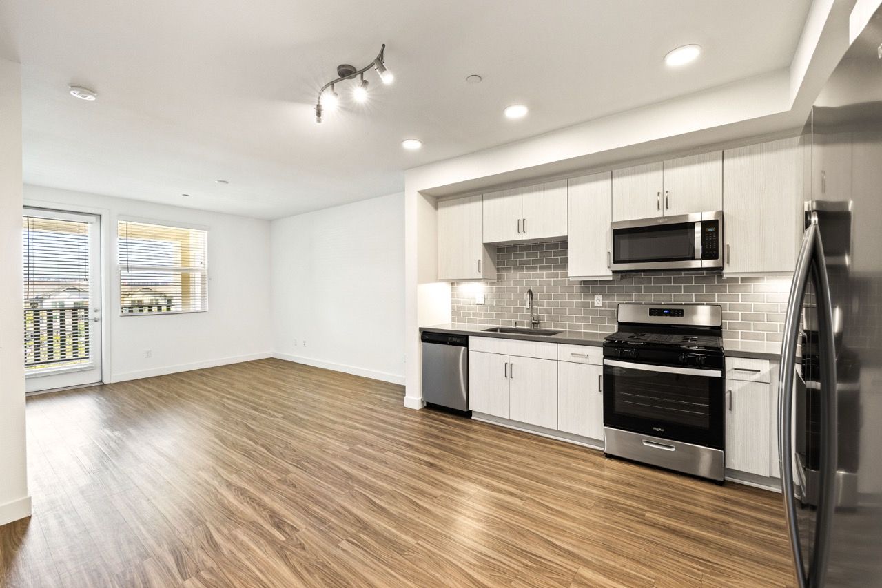 Open-concept kitchen with stainless steel appliances and wood-look flooring.