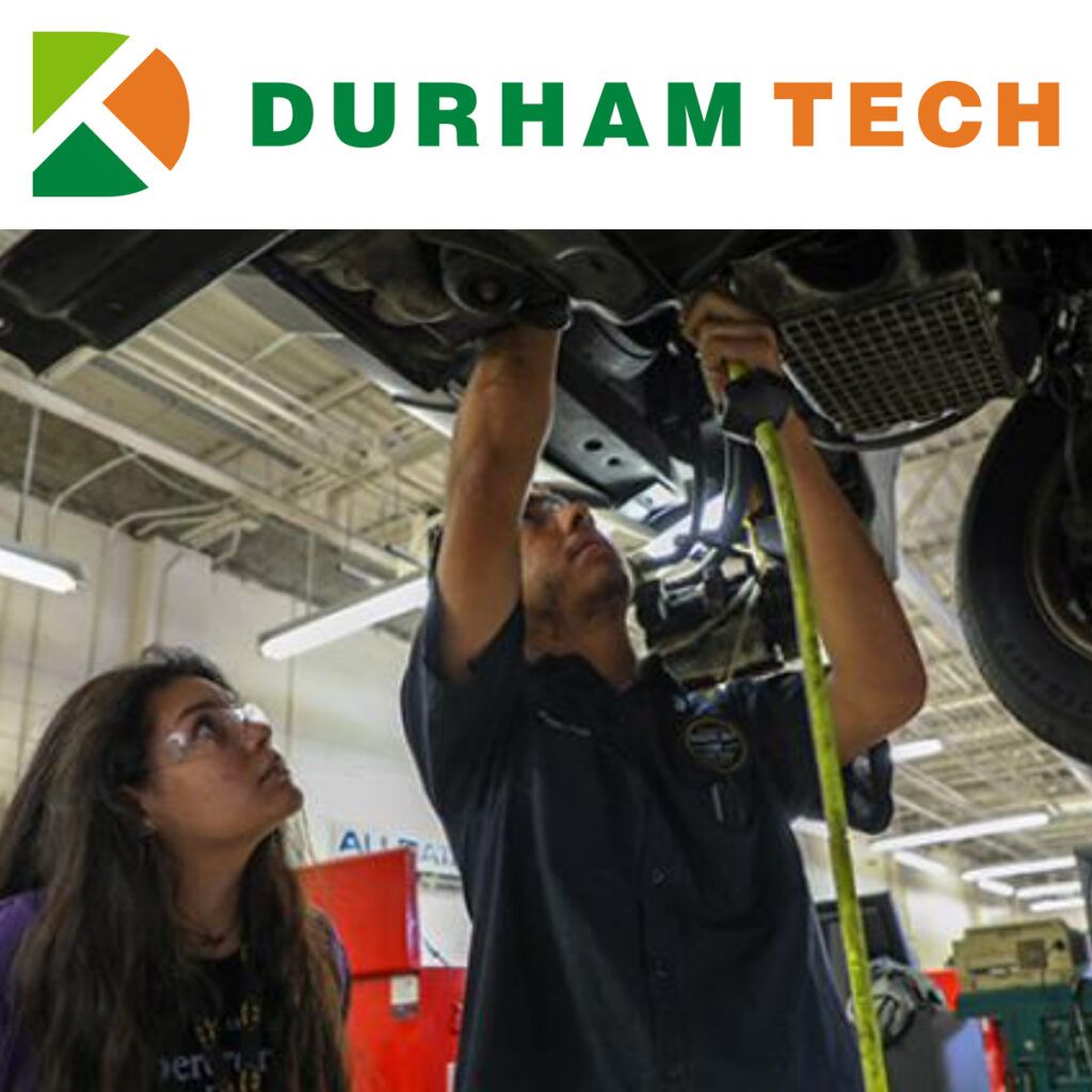 Two people working on a car in a shop at Durham Tech. One is working under the car while the other observes.
